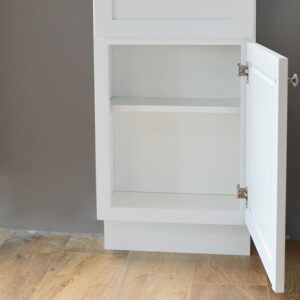 White kitchen cabinet with open door on wooden floor.