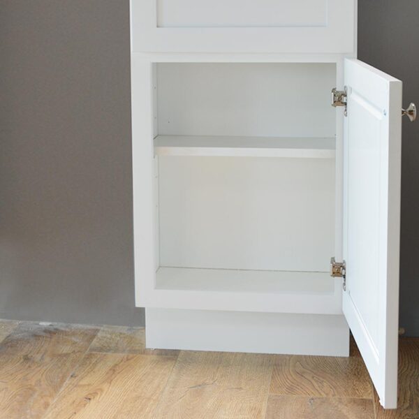 White kitchen cabinet with open door on wooden floor.