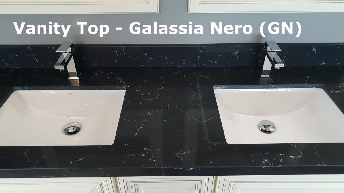 Black vanity top with two sinks and modern faucets.