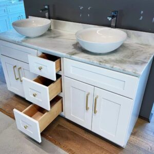 Double sink vanity with open drawers in a modern kitchen showroom.