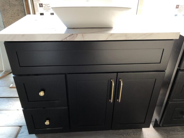 20220317152115-scaled-1.jpg Black kitchen cabinet with marble countertop and white sink.