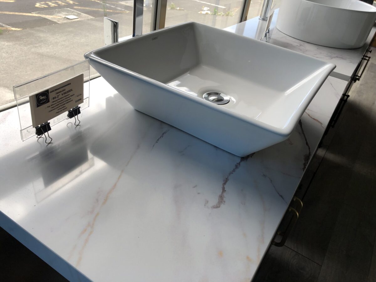 Square white sink on marble countertop in showroom.
