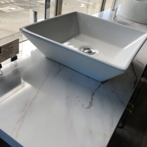 Square white sink on marble countertop in showroom.