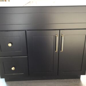 Black kitchen cabinet with gold handles and drawers.