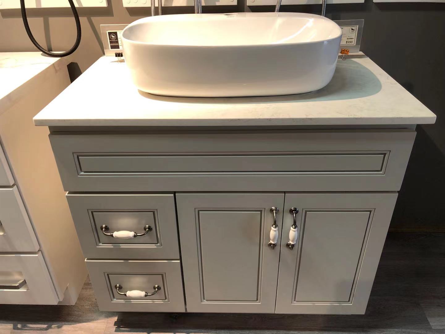 White bathroom vanity with drawers and a countertop sink.