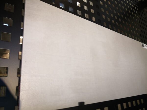 Large gray tile displayed on a black perforated metal stand.