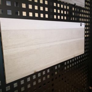 Tile sample displayed on a black perforated board.