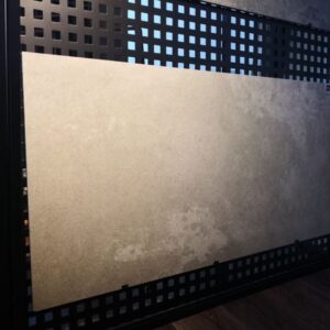 Tile sample displayed on a black grid panel in a showroom.