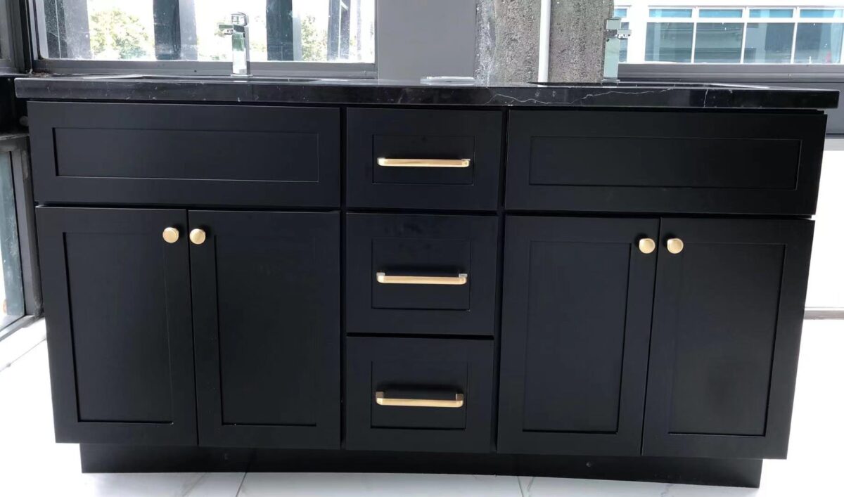 Black marble kitchen cabinet with gold handles in modern setting.