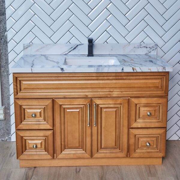 COG-V4720D-1-1.jpg Wooden bathroom vanity with marble countertop against herringbone tile wall.