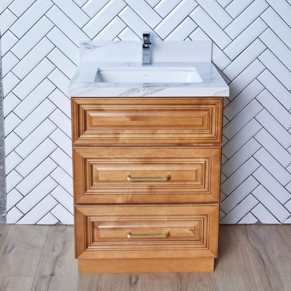 Wooden bathroom vanity with white sink and herringbone tile background.
