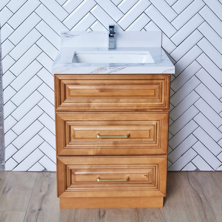Wooden bathroom vanity with white sink and herringbone tile background.