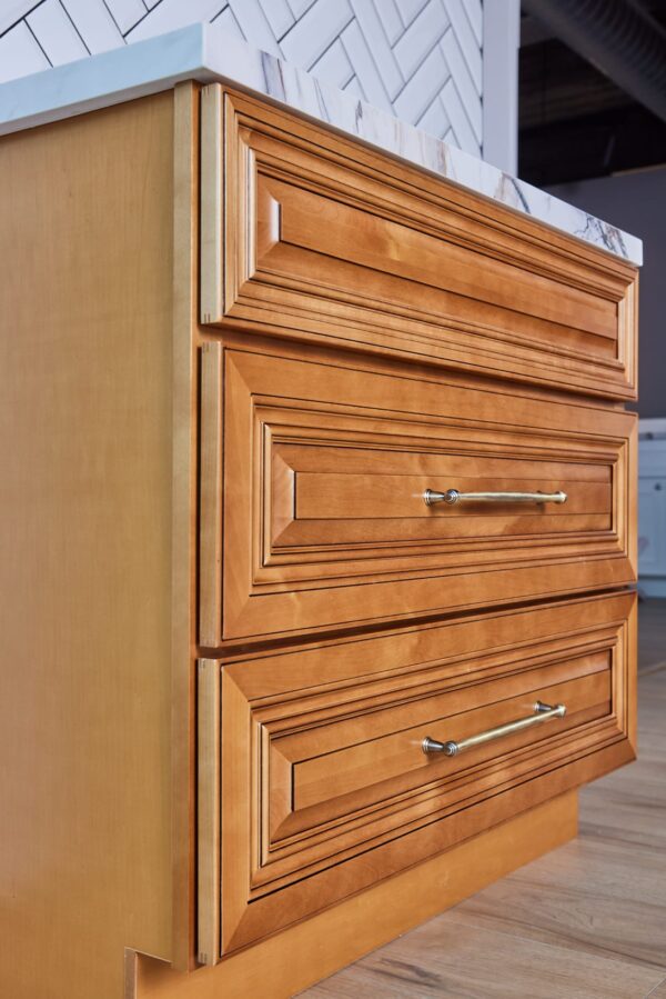Wooden kitchen cabinet with three drawers and metal handles.