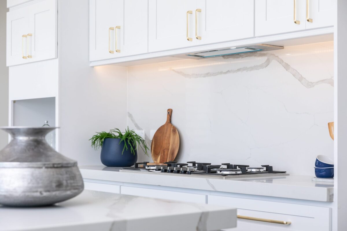Modern kitchen with white cabinets and marble countertops.