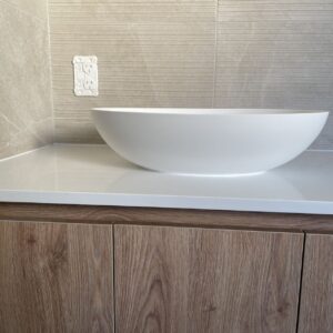 Custom bathroom vanity with white basin and wood cabinets.