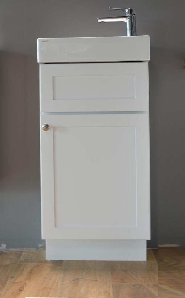 White kitchen cabinet with a single door and silver knob.
