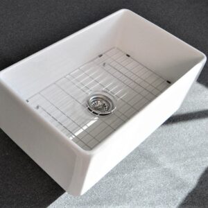 White kitchen sink with metal grid on dark countertop.