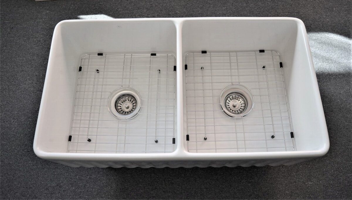 Double kitchen sink with metal grids and drains.