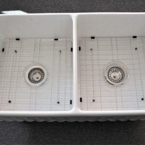 Double kitchen sink with metal grids and drains.