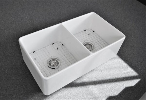Double bowl white kitchen sink on gray countertop.