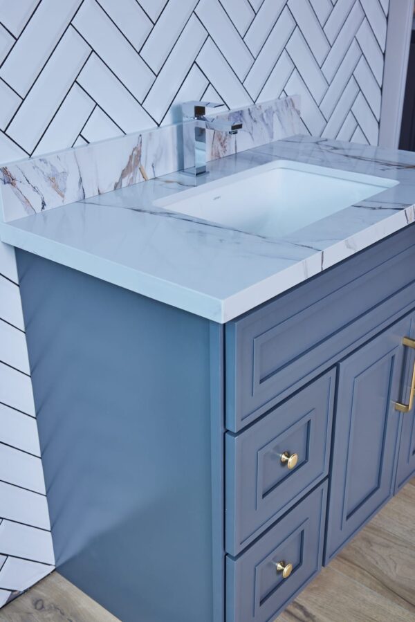 Blue bathroom vanity with marble countertop and modern faucet.