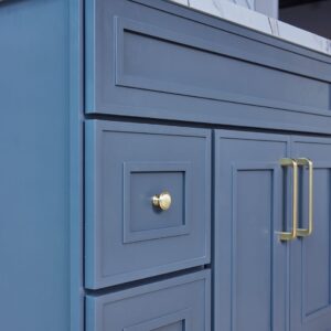 Blue kitchen cabinet with gold handles and marble countertop.