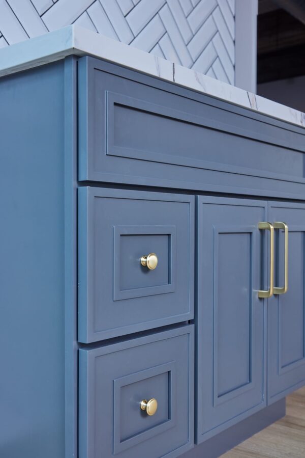 Blue kitchen cabinet with gold handles and marble countertop.
