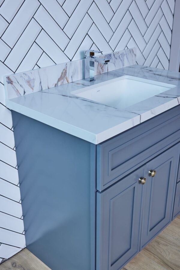 Blue bathroom vanity with marble countertop and modern faucet.