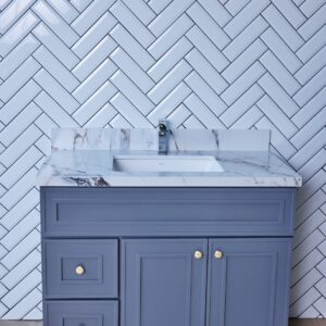 Blue bathroom vanity with marble countertop and herringbone tile backsplash.