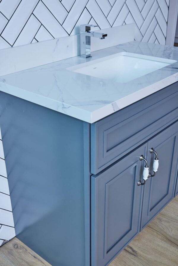 Blue bathroom vanity with marble countertop and silver handles.