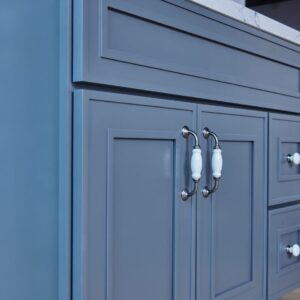 Blue kitchen cabinet with white handles and marble countertop.