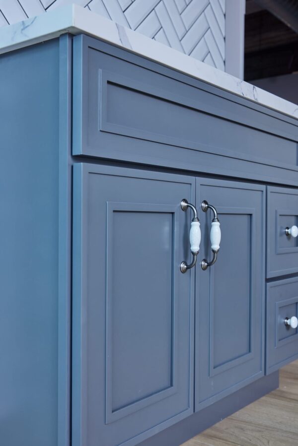 Blue kitchen cabinet with white handles and marble countertop.