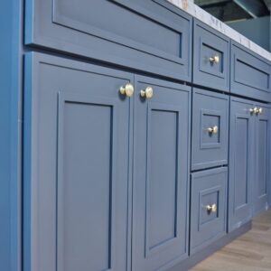 Blue kitchen cabinets with gold handles and marble countertop.