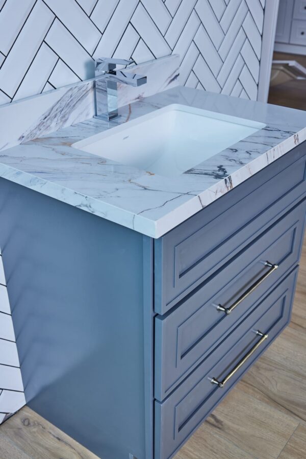 Blue bathroom vanity with marble countertop and modern faucet.
