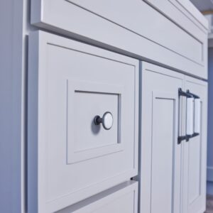 White kitchen cabinets with modern handles and a marble countertop.