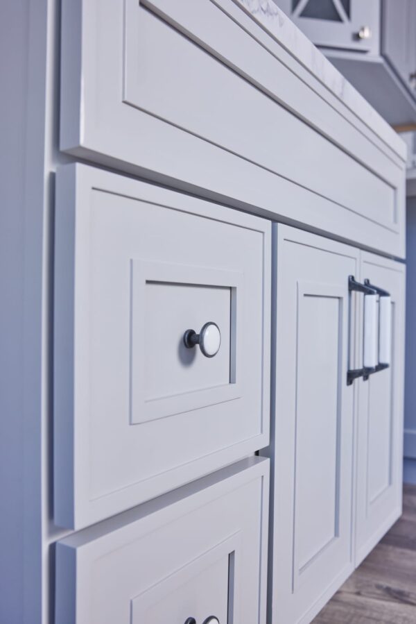 White kitchen cabinets with modern handles and a marble countertop.