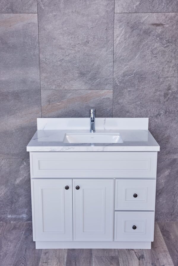 White bathroom vanity with marble countertop and gray tiled wall background.