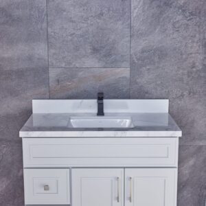 White bathroom vanity with marble countertop against gray stone wall.