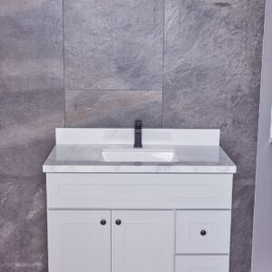 White bathroom vanity with marble countertop and gray tiled wall background.