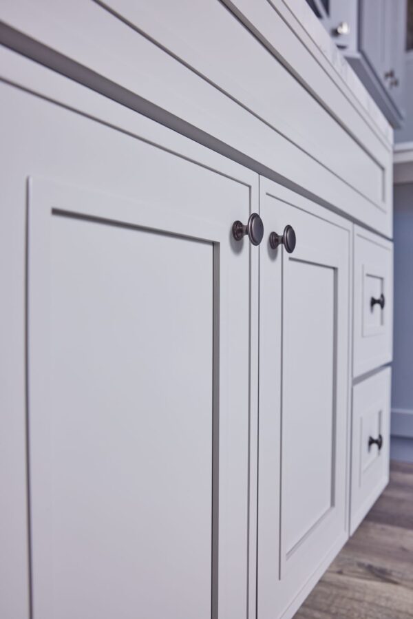White kitchen cabinets with modern handles, close-up view.