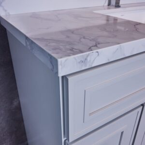 Marble countertop with modern faucet and light gray cabinet.