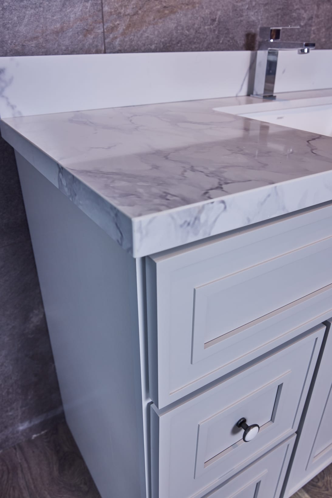 Marble countertop with modern faucet and light gray cabinet.