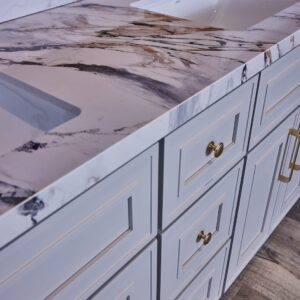 Marble countertop with white cabinets and gold handles in a modern kitchen.