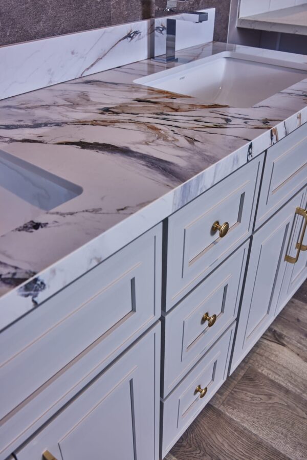 Marble countertop with white cabinets and gold handles in a modern kitchen.
