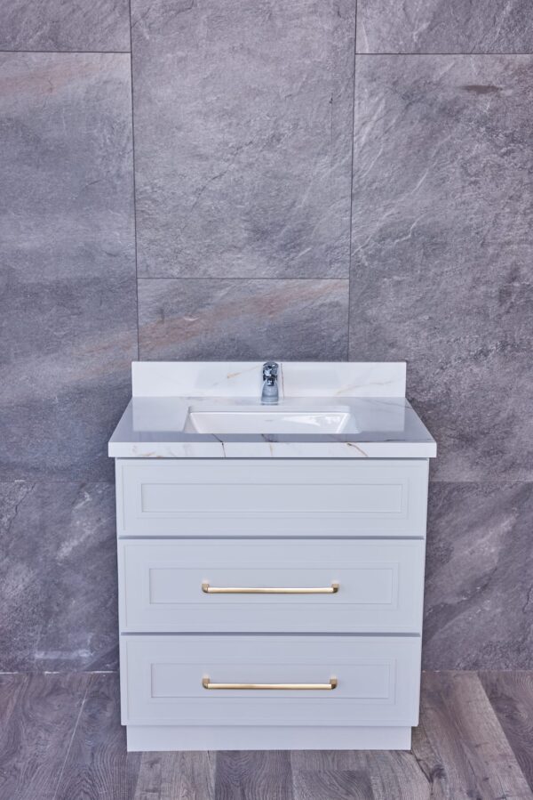 Modern bathroom vanity with marble countertop and gray tile background.