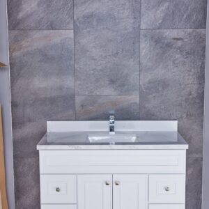 White bathroom vanity with marble countertop against gray tiled wall.