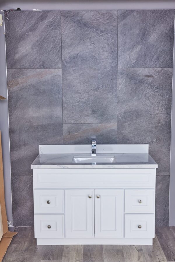 White bathroom vanity with marble countertop against gray tiled wall.