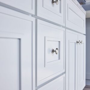 White kitchen cabinets with silver knobs.