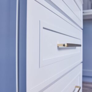 White kitchen cabinet with gold handles, close-up view.