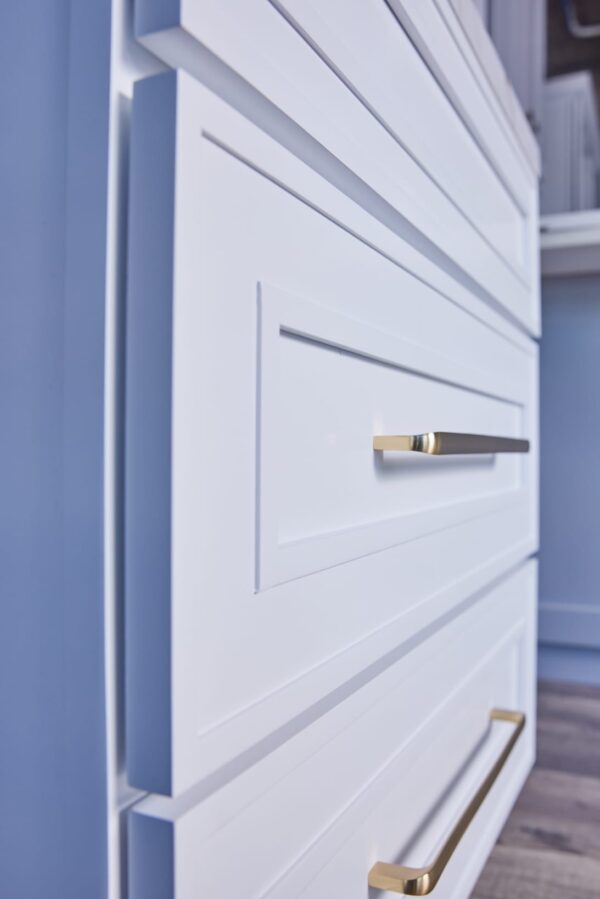 White kitchen cabinet with gold handles, close-up view.
